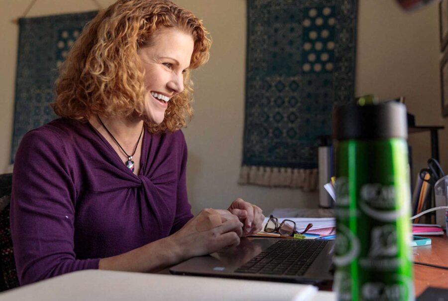 about us, female staff member smiling at her computer, triad clinical trials